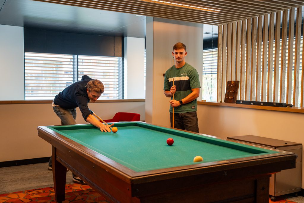 Collega's van REUS spelen samen biljart op kantoor