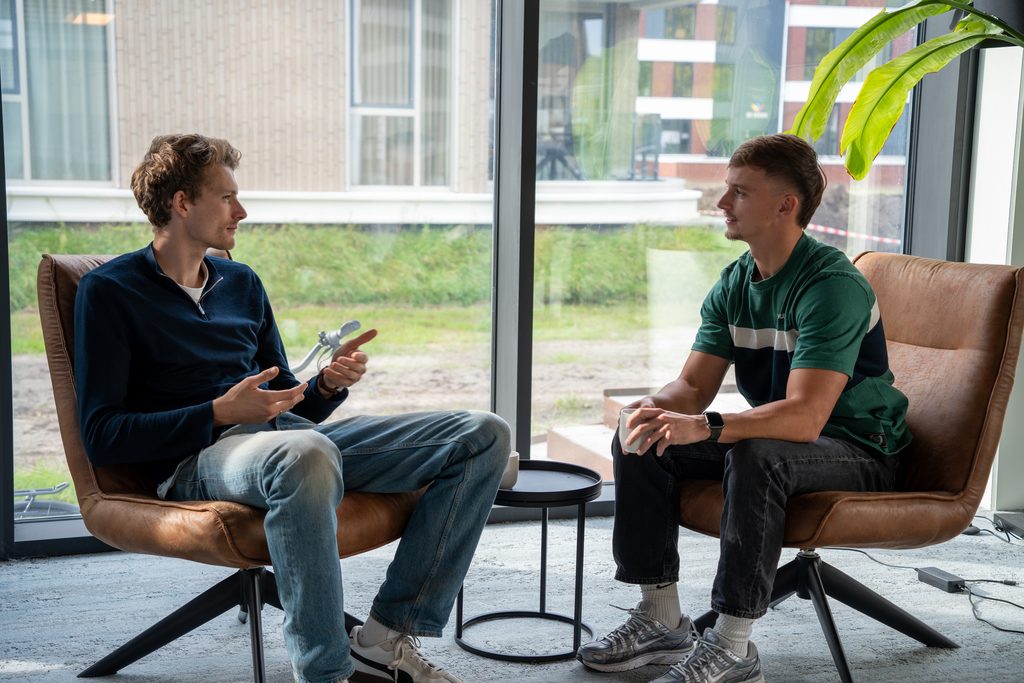 Twee collega's van REUS in overleg bij het raam