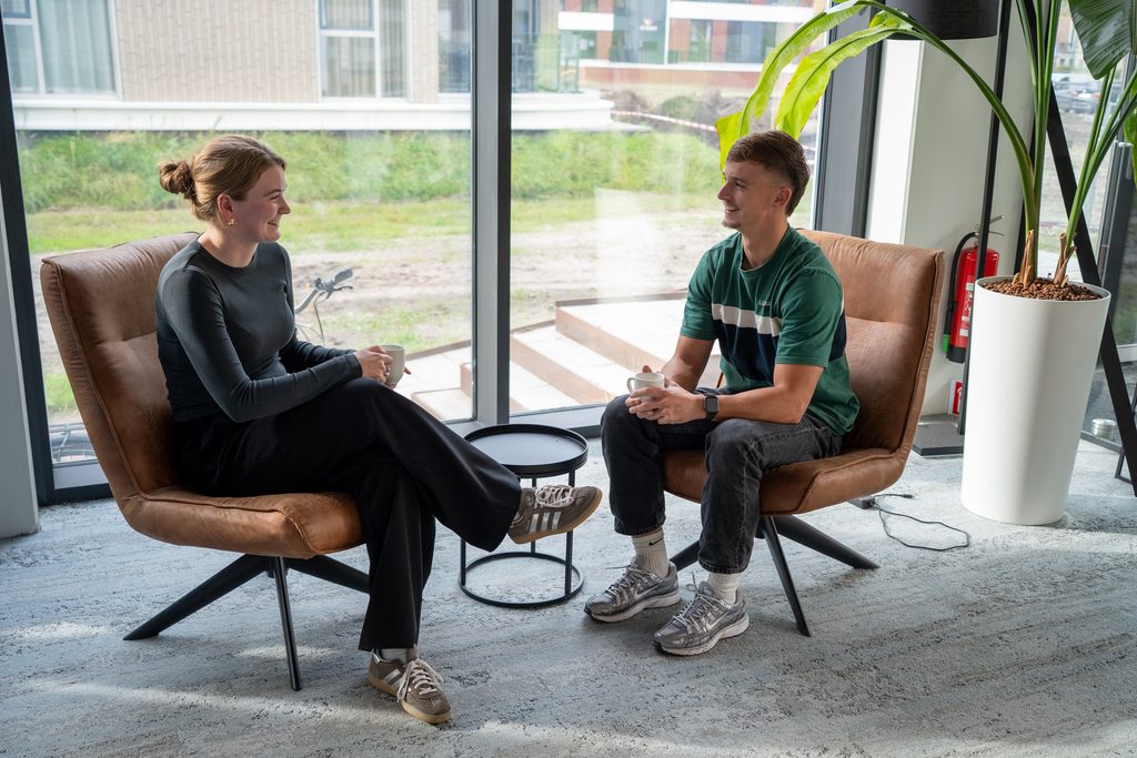 Twee collega's van REUS in gesprek in de lounge