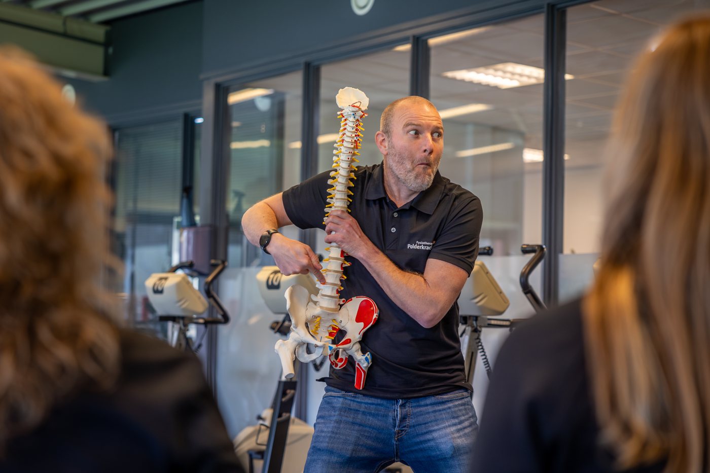 Fysiotherapeut geeft uitleg met een model van de wervelkolom