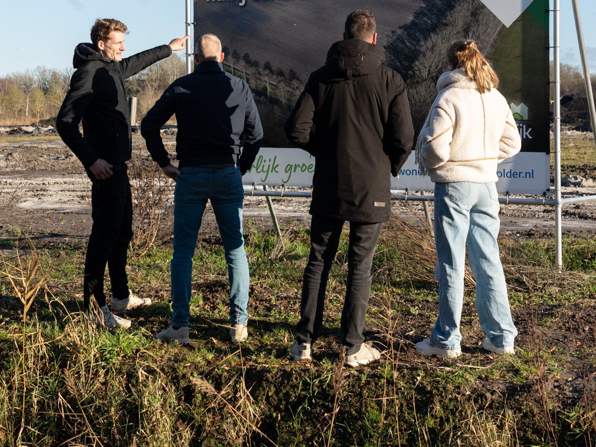 Woningzoekers bij een bouwbord op de bouwlocatie