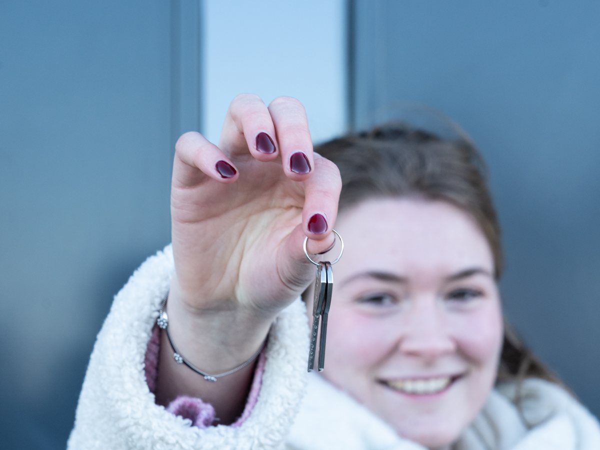 Vrouw houdt trots de sleutel van haar nieuwbouwwoning omhoog