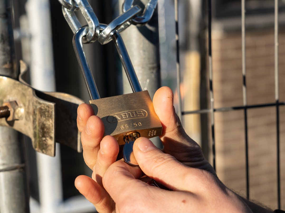 Hangslot aan een bouwhek wordt geopend