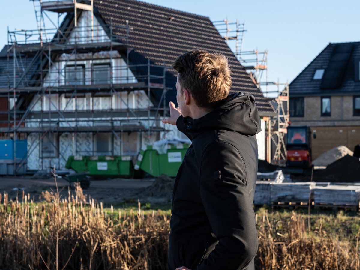 Man wijst naar een nieuwbouwwoning in aanbouw