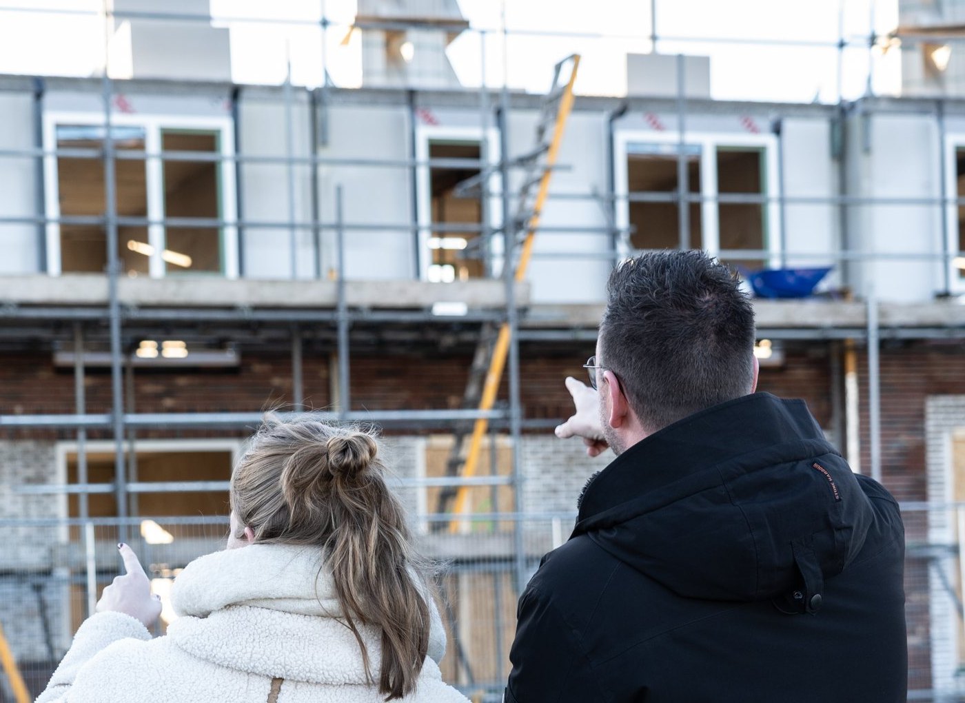 Stel bekijkt nieuwbouwwoningen in aanbouw