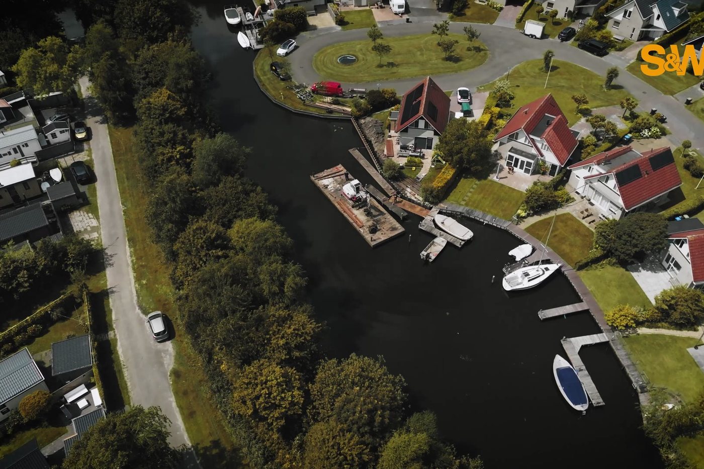 Dronebeeld uit de commercial: steigers en boten in een woonwijk aan het water