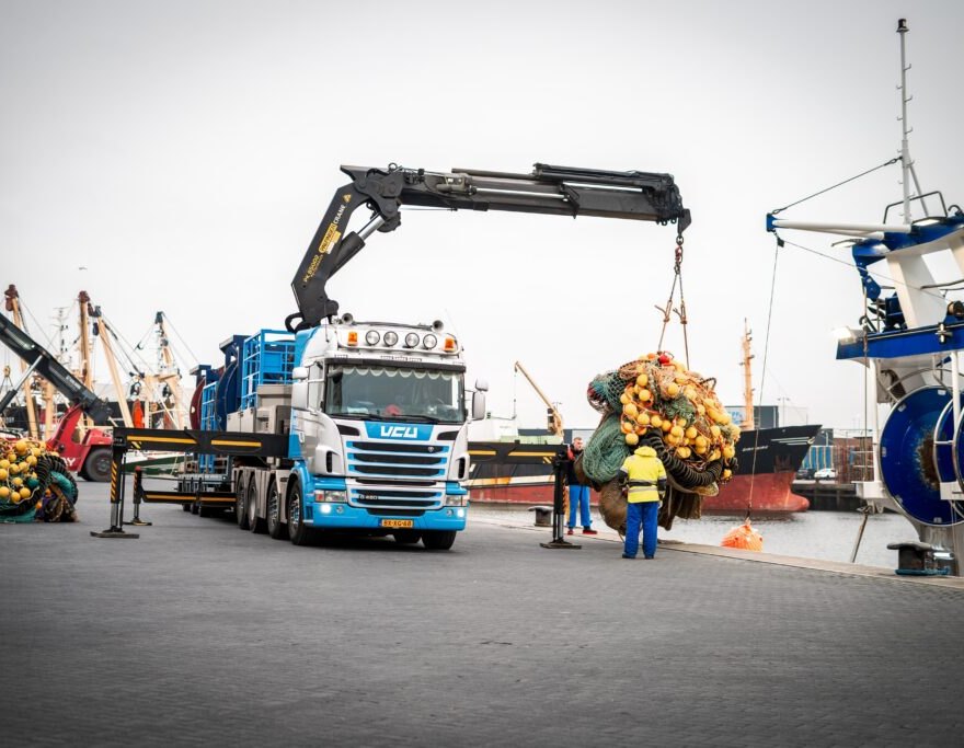 Vrachtwagen van VCU lost visnetten op de kade in Urk