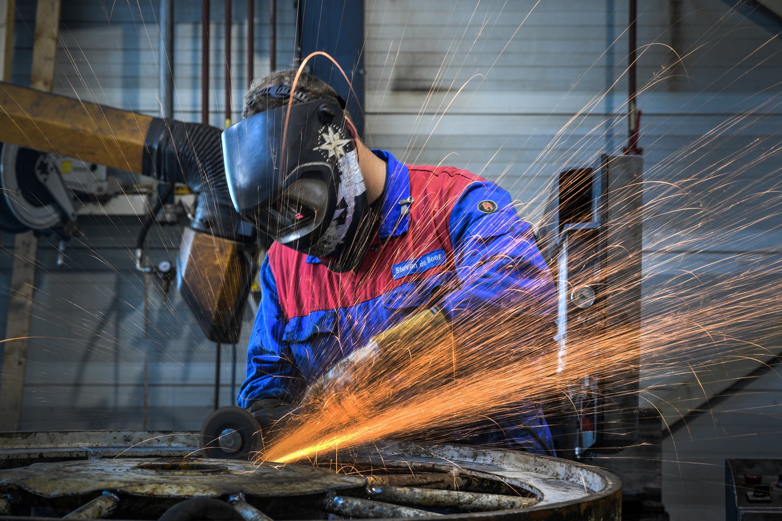 Medewerker van VCU aan het slijpen in de machinefabriek